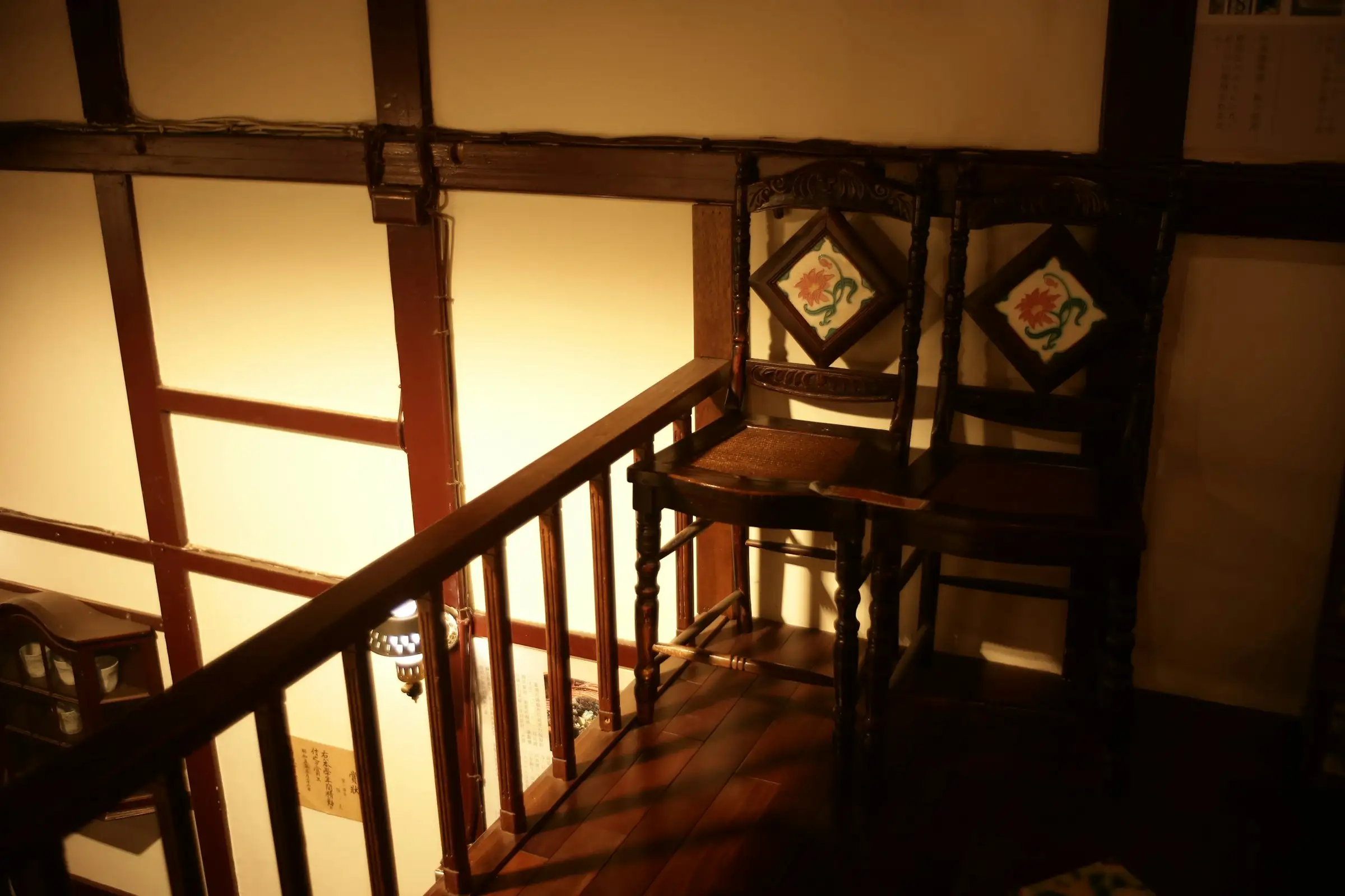 Two antique chairs on a wooden landing at the top of a staircase