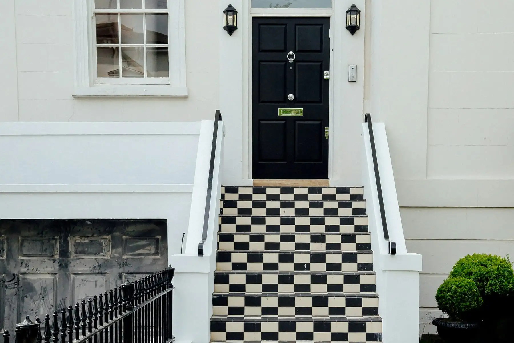 A black front door above chequered tiled steps in London